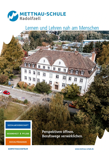  Frontansicht eines großen weißen Gebäudes mit mehreren Fenstern und einem braunen Dach, umgeben von Bäumen, mit der Aufschrift „METTNAU-SCHULE Radolfzell“ am oberen Rand. 